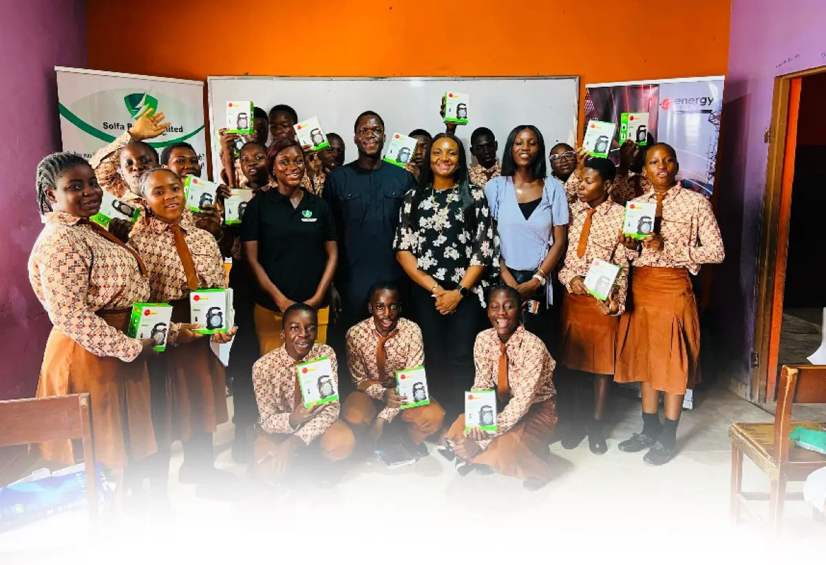 Solfa Power team and students holding solar lamps together indoors