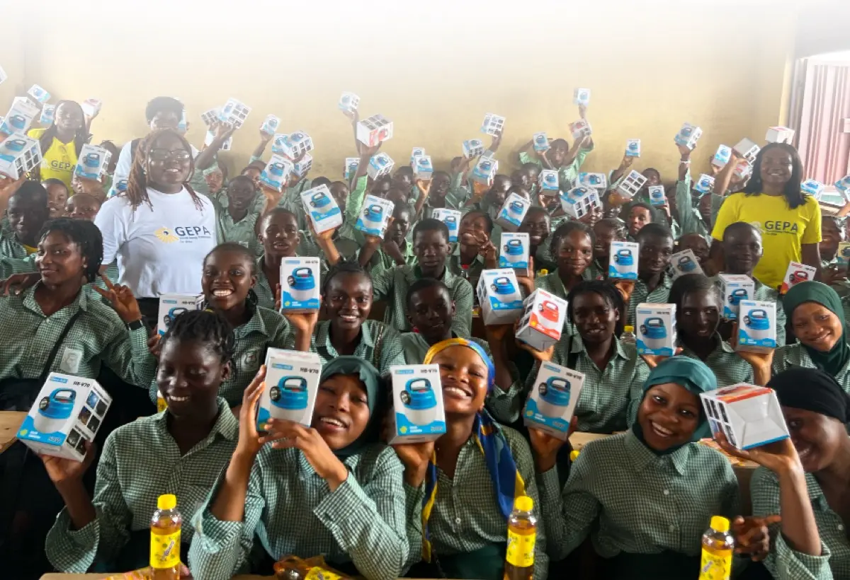 A classroom of students holding Solfa Power solar lamps